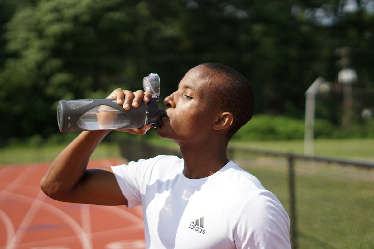 Man drinking water from a sports bottle during a training break